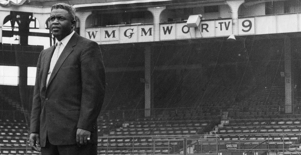 Jackie Robinson in a suit on a baseball field